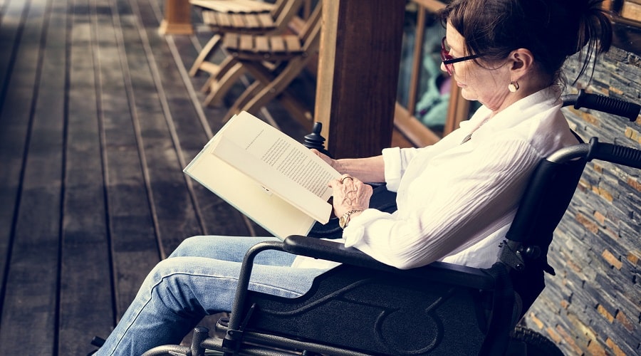 A woman sitting on a wheelchair and reading